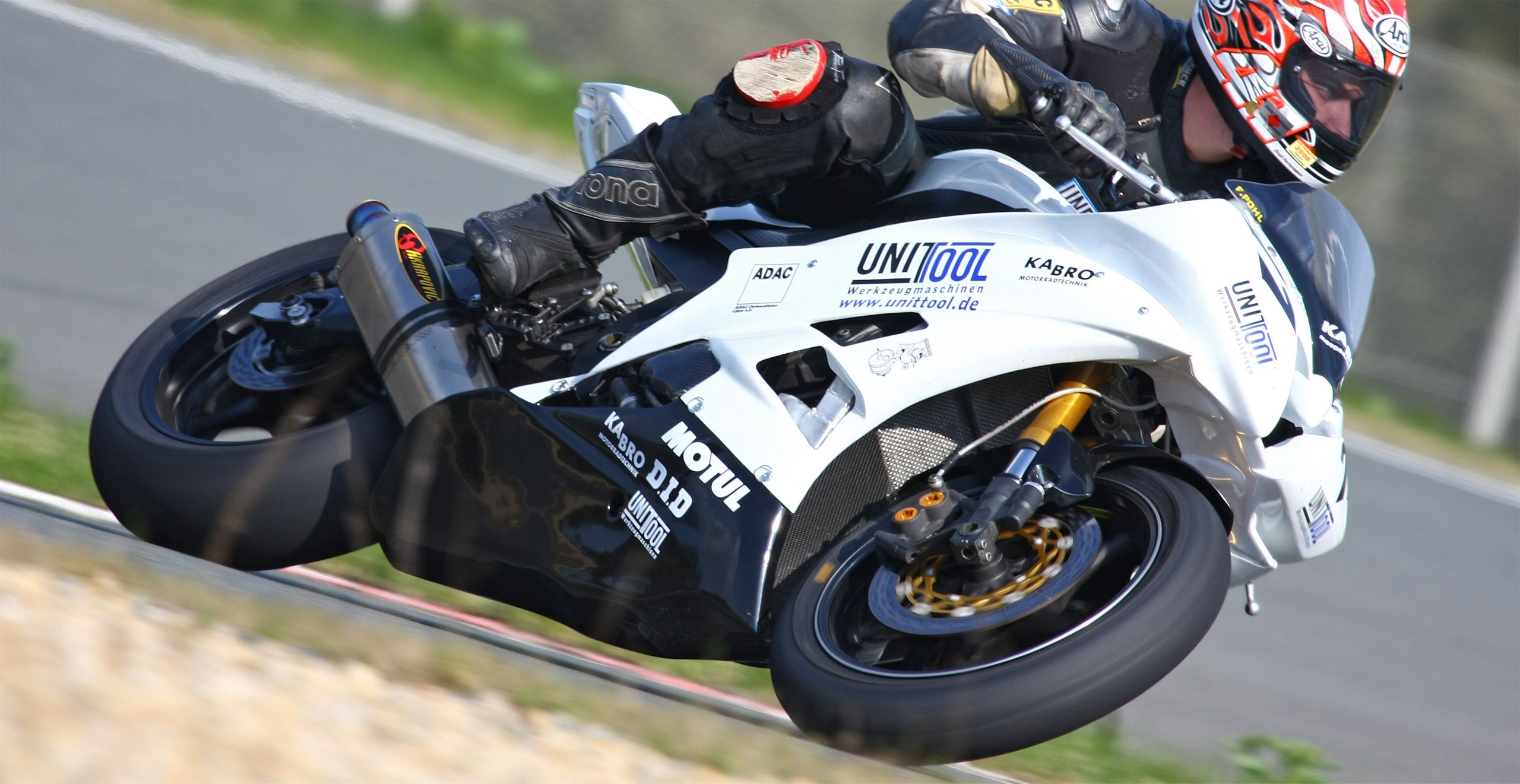 Ein Motorradfahrer mit einem weißen Motorrad, in einer Kurve